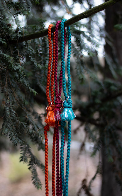 Na fotce jsou 3 paracordová vodítka s ručkou vhodné pro malé psy svou lehkostí a šířkou. Barvy vodítek jsou cihlová, vínová a tmavě tyrkysová. Vodítka jsou opatřeny kroužkem pro připnutí kolem těla a zdobným přívěskem.